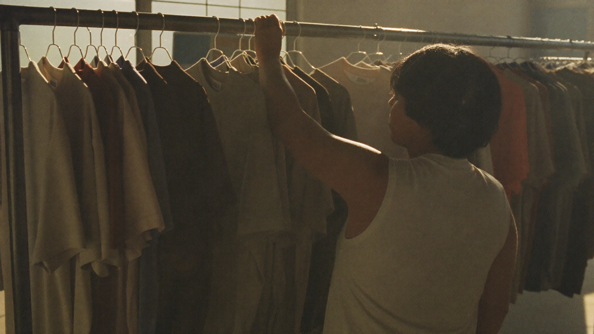 A long rail of plain tees in a sunlit studio