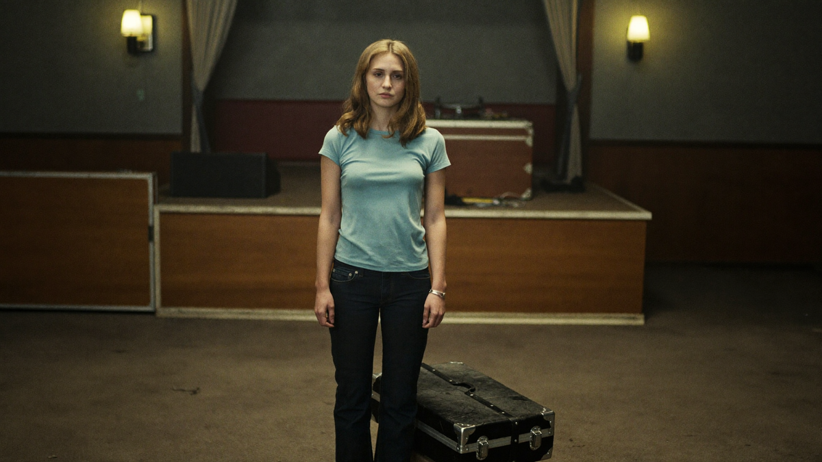 A musician beside a small stage in an empty tavern back room