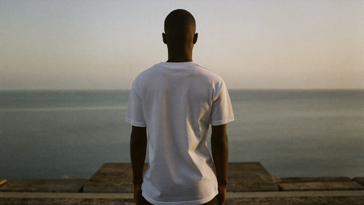 A figure at the top of worn stone steps facing a grey sea at dawn
