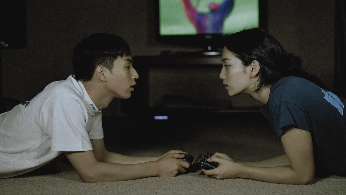 Two friends on the carpet of a dark room lit by the glow of a television