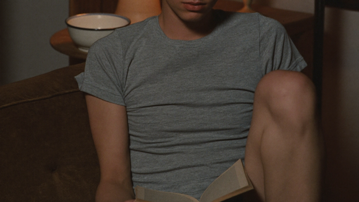 Someone sunk into the corner of a worn couch late at night with a book
